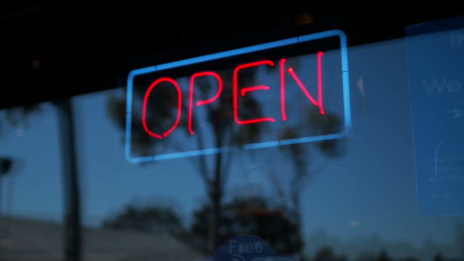 A neon Open sign lit in a window at dusk